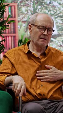 Vertical Video Nurse jumping to help senior man in wheelchair losing conscience during home visit, old person hyperventilating and scaring his wife. Medical assistant in panic checking the pulse