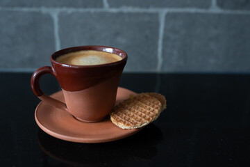 Brown cookies are lying next to the arabica coffee in a brown cup.