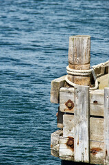 Wooden mooring pole with knotted rope on a quay by the Baltic Sea in southern Sweden in the summer.