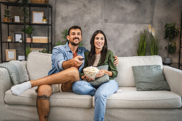 Obraz premium adult couple watch movie, series on television and eat popcorn at home