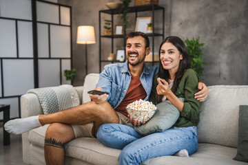 adult couple watch movie, series on television and eat popcorn at home