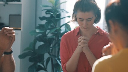 Top view of skilled diverse prayer clasping hand and praying to god while sitting at chair in circle. Top down aerial view of people folded hand while sitting with opened bible on laps. Symposium.