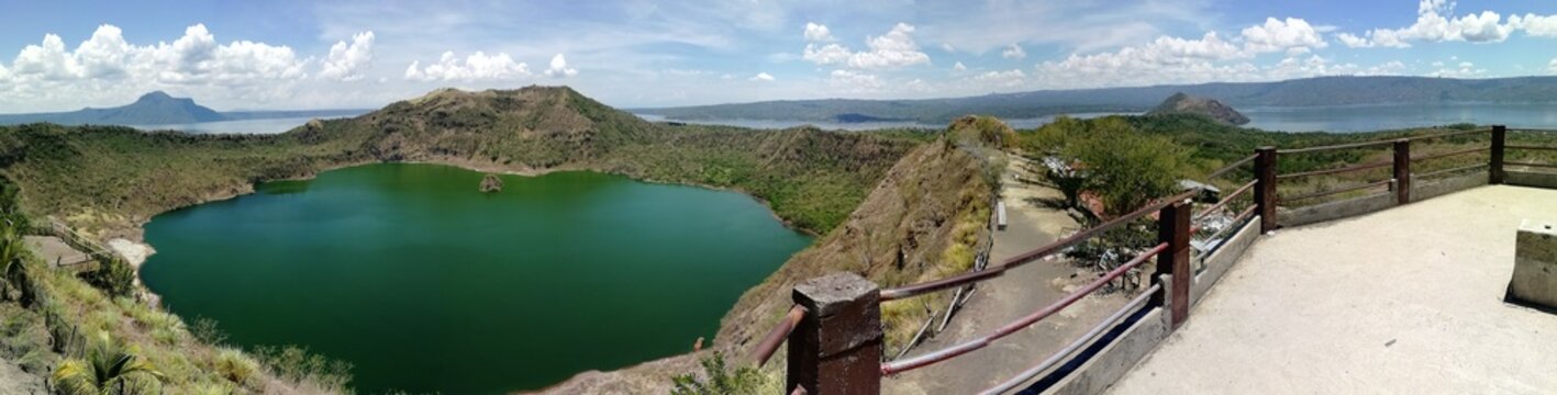 Panoramic view of Taal Lake from Binintiang Munti, Philippines, showing calm water, volcanic landscape, surrounding hills, and a scenic tropical environment.