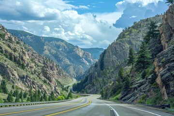 Fototapeta premium Scenic mountain road with lush greenery and blue sky.