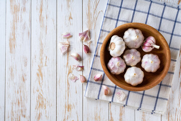 garlic in a wooden bowl on a white kitchen table, top view