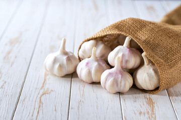 fresh garlic in a sack on a wooden table with copy space for text.