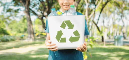 Cheerful young asian boy holding recycle symbol bin on daylight natural green park promoting waste recycle, reduce, and reuse encouragement for eco sustainable awareness for future generation. Gyre