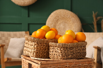 Wicker baskets with citruses on rattan box in green living room