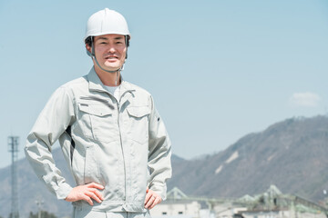 ヘルメットを被った作業着姿のアジア人男性作業員
