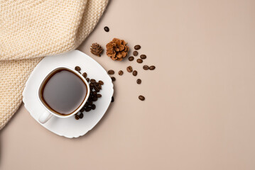 Cup of coffee, coffee beans, cones and scarf on beige background. Copy space. Flat lay, top view