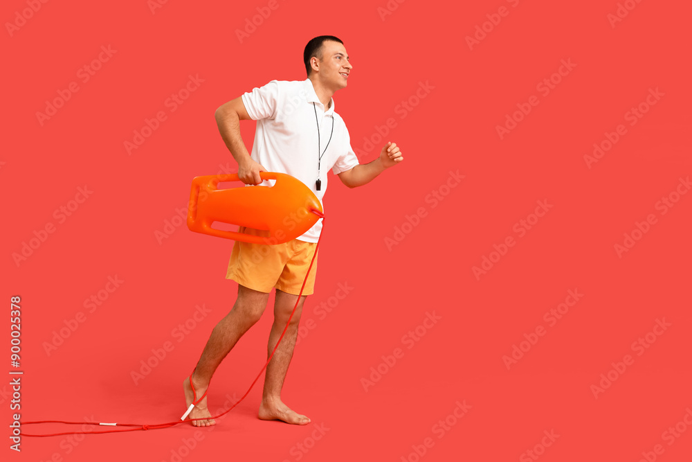 Wall mural Handsome happy male lifeguard with life board on red background