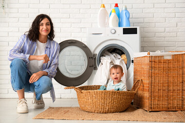 Mother with her cute little baby doing laundry in bathroom