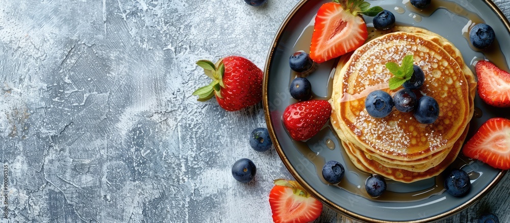 Poster top down view of a plate with a stack of breakfast pancakes garnished with fresh blueberries and str
