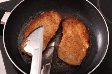 Schnitzels cooking in frying pan on stove, top view