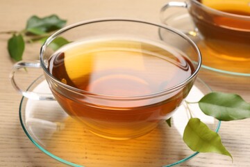 Refreshing green tea in cups and leaves on wooden table, closeup