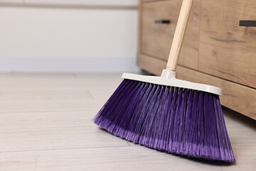 Sweeping wooden floor with bright broom indoors