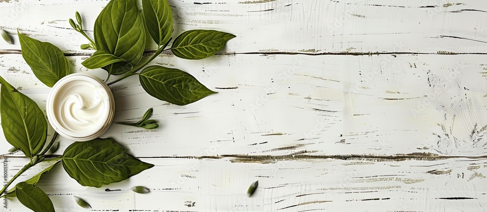 Poster cosmetic cream placed on a fresh herbal leaf with a white wood background creating an elegant compos