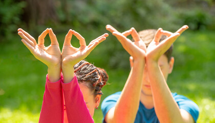 couple meditating doing yoga in nature.man and woman doing yoga exercises meditating on green grass