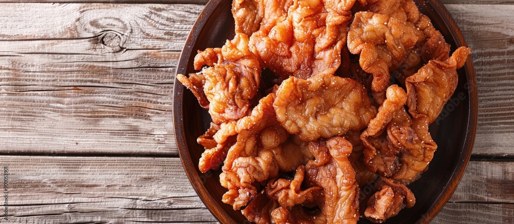 Aufkleber Crunchy fried pork cracklings displayed on a wooden surface with room for text in the image. with copy space image. Place for adding text or design