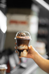 hand of woman holding a take-out iced affogato chocolate at coffee shop.