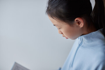 Obraz premium 家のリビングで読書する小学生の子供の姿