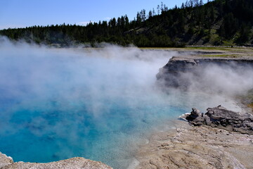 Excelsior Geyser hot spring with steam in the Midway Geyser Basin of Yellowstone National Park in...