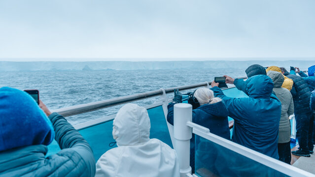 Antarctica - December 26th 2023 - Photo of A23a Iceberg from Cruise Ship Behind Crowd. Passengers Hold Up Cell Phones to Photograph it