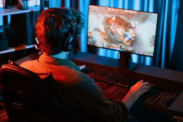 Host channel of young gaming streamer playing fighting Moba at battle arena game with multiplays team, wearing headphone on pc monitor with back side image at neon digital light modern room. Gusher.