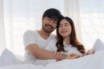 Young asian couple is sharing a tender moment while lying in bed with their eyes closed