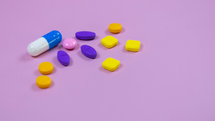 Assorted pharmatheutical multicolored medicinal capsules, pills used in medical treatment on pink background . Colorful pills and capsules. Healthcare and medical concept. Space for text.