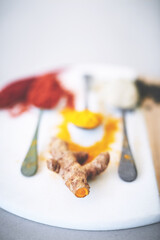Board, spices and ginger on table with spoon, seasoning and ingredients for meal with powder. Fresh, collection and condiment with flavor for cooking, turmeric and paprika in Indian culture for aroma