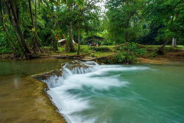 Obraz premium camping tent on nature waterfall and motion flow stream water in green trees forest for summer holiday relax and vacation travel with trekking picnic at Huai Mae Khamin Waterfall campground Thailand