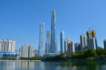 Obraz premium Skyscrapers Reaching into a Bright Blue Sky with White Clouds on a Sunny Day
