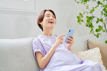 自宅で想像しながらスマートフォンを使う高齢妊娠をした妊婦