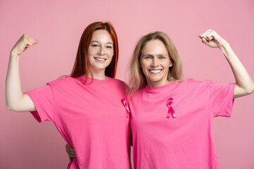 Women showing biceps on hands wearing pink t shirts with pink ribbons for breast cancer awareness