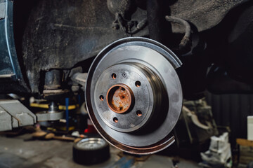 The rim is removed showing the rotor and caliper. Disc brake on car in process of new tire...
