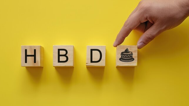 HBD wooden block and cake icon for happy birthday celebration on yellow background.