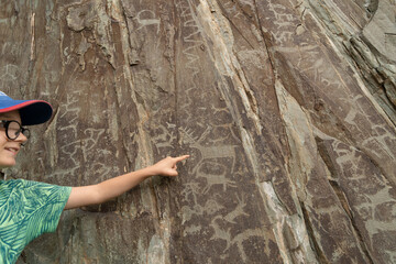  Ancient paintings petroglyphs and little boy in the Altay mountains, Russia