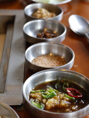 Korean bbq garlic dipping sauces in metal bowls on wooden table