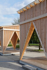 Close up of modern wooden arbor, gazebo. Green tree foliage on the back. Sunny day during summer time. Pirita, Tallinn, Estonia, Europe. July 2024