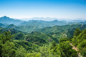 Naklejka premium A picturesque scene of the Great Wall of China snaking through lush green mountains, under a clear blue sky