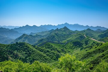 A picturesque scene of the Great Wall of China snaking through lush green mountains, under a clear blue sky