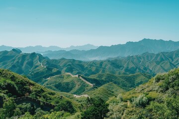 Fototapeta premium A picturesque scene of the Great Wall of China snaking through lush green mountains, under a clear blue sky