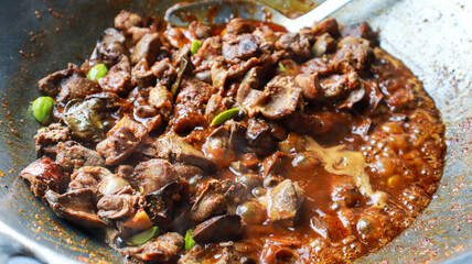 Chicken gizzards being stir-fried in a wok, a delicious and flavorful dish. Chicken Gizzards and liver Stir Fry background.