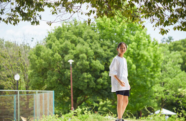 夏休みの公園で散歩する一人の小学生の子供の様子