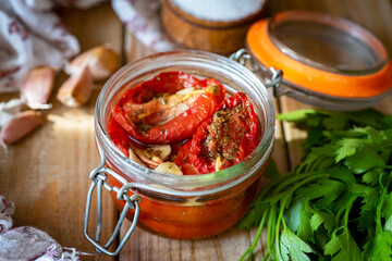 Dried tomatoes in a glass jar on a wooden table. Close-up