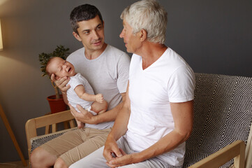 Happy Caucasian man young father vising ting his old dad with grandchild family resting indoors...
