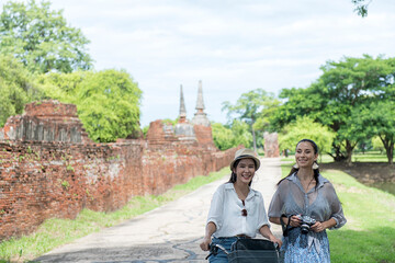 Fototapeta premium Woman travel in historical temple with bicycle. Tourist Travel taking a photo temple in Ayutthaya historical Park UNESCO world heritage site. 