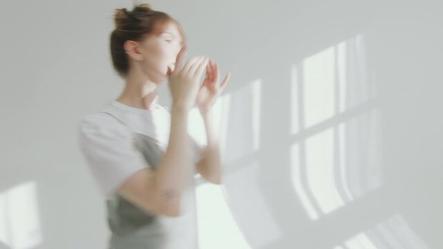 Professional photographer giving directions to beautiful female model, telling how to pose during photo session in studio with white cyc wall
