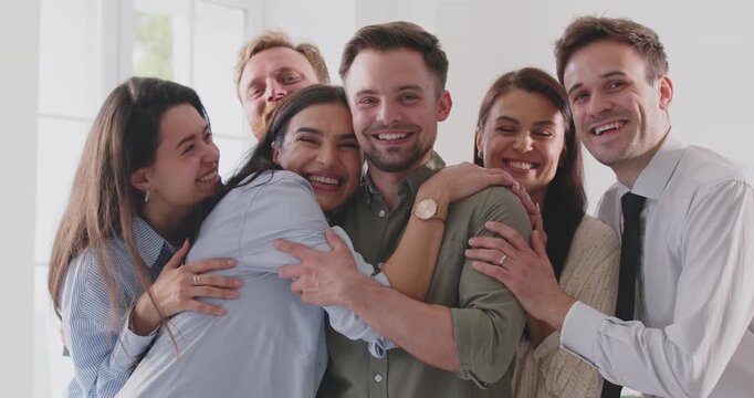 Excited diverse friends, coworkers embrace and greeting male buddy coming at meeting, group hugging guy laughing to support, welcoming at students reunion, life friendship or team looking at camera